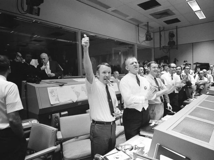 Flight Director Gerry Griffin raises his arm for a thumbs up in the foreground in this scene from the Mission Control Center at what is now Johnson Space Center. Next to him are fellow flight directors for the Apollo 13 mission, Eugene Kranz and Glynn Lunney, both clapping hands. Flight controllers and mission leaders celebrate the successful return of the Apollo 13 crew on April 17, 1970. Credit: NASA