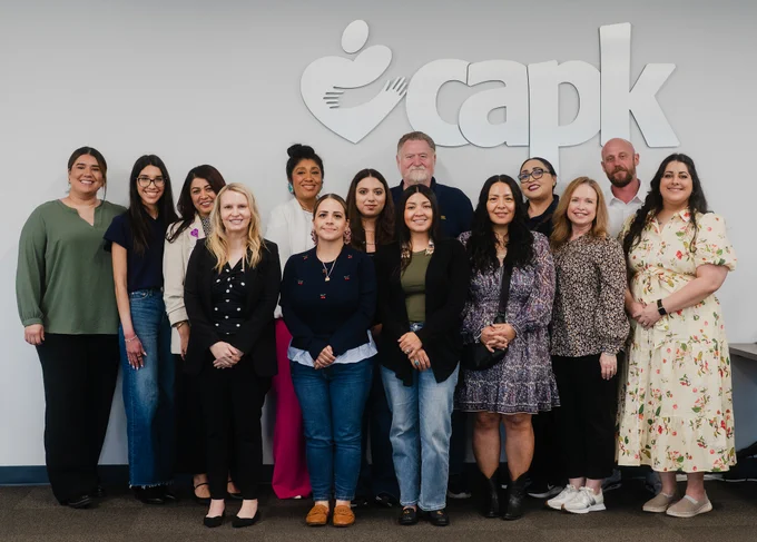 RAMP mentors and mentees pose for a photo in front of the CAPK logo. 