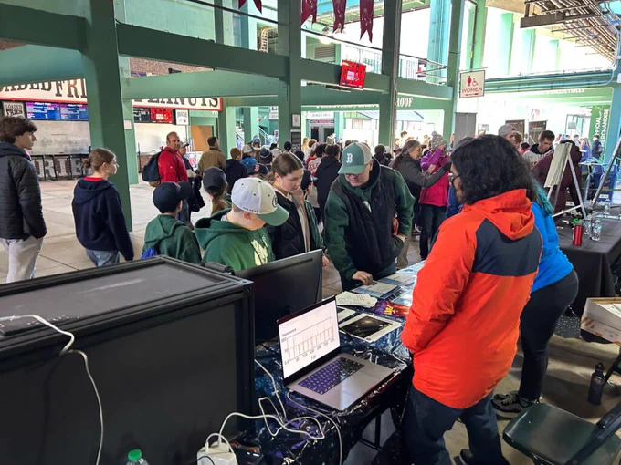 TESS@MIT volunteers Kiran and Katharine hand out informational posters and use flash cards to help demonstrate how TESS finds planets around distant stars at Fenway Park.