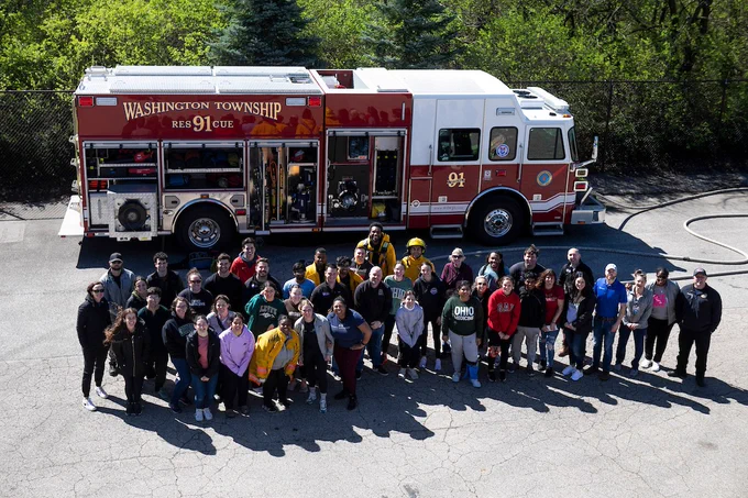 A large group of medical students and emergency responders posing for a photo in front of a Washington Township fire truck.