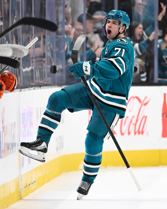 Macklin Celebrini celebrating on ice in a Sharks uniform.