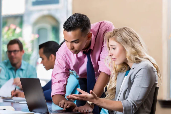 photograph of a man showing a woman how to use a computer