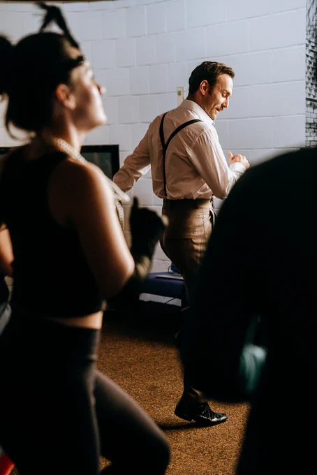 People wearing flapper accessories dance in a small hall.
