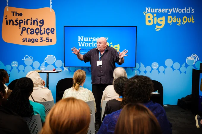 A person stands in front of an audience giving a presentation at Nursery World's Big Day Out event. The backdrop includes the event logo and a sign that says "The Inspiring Practice stage 3-5s." The audience is seated, facing the speaker.
