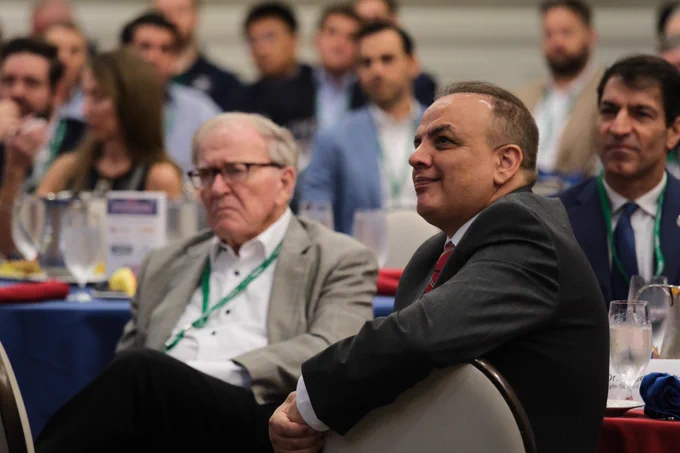 Dr. Saeed Salehi and Dr. Bobby B. Lyle sit at the table and look up at the speaker from their seats at the Summit