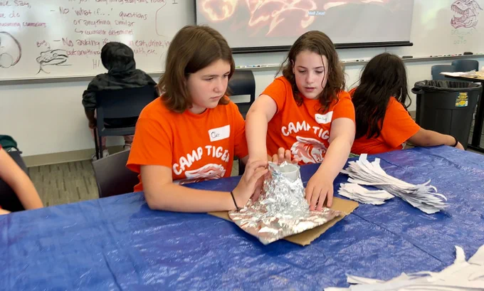 Two children use tin foil to make a volcano 