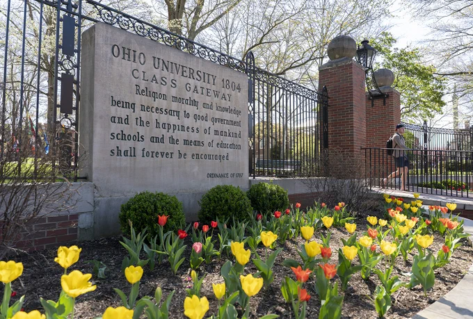 Class Gateway on College Green with yellow and orange flowers blooming in front of it 
