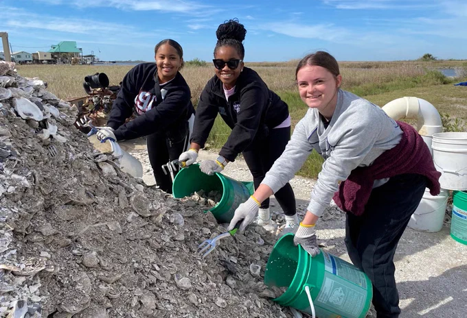 Three individuals seen doing a service project during the Beyond Bama Spring Break trip.