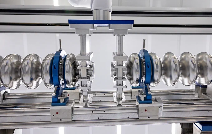 A detailed view of a scientific or industrial apparatus with metallic spherical components arranged symmetrically. The setup includes blue and silver elements, possibly part of a laboratory or manufacturing equipment. The background is a clean, well-lit environment.