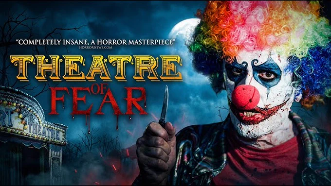 actor Nathan Head in full clown makeup promoting his 2014 film Theatre of Fear, he holds up a knife and has blood splatters on his face and red nose, he wears a rainbow wig and it's a full moon in the sky.
