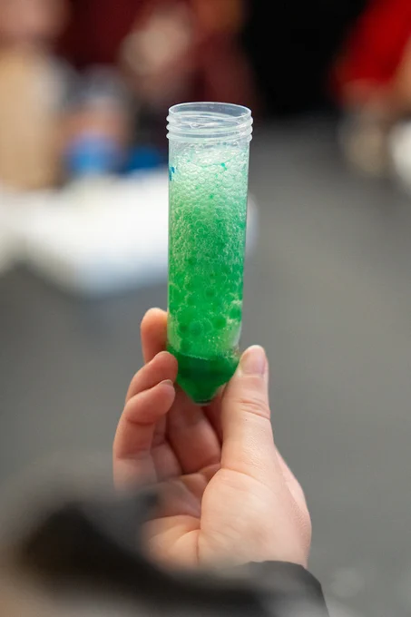 Hand holding green science experiment.