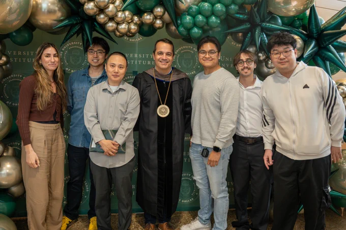 Dr. Bleris's lab in a group photo with Dr. Bleris and his award in front of a green backdrop and balloon arch.