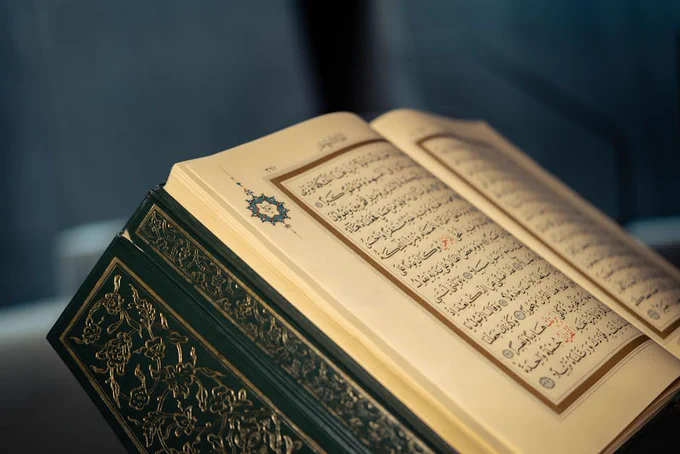 Close-up of an open Quran displaying intricate Arabic calligraphy on a page.