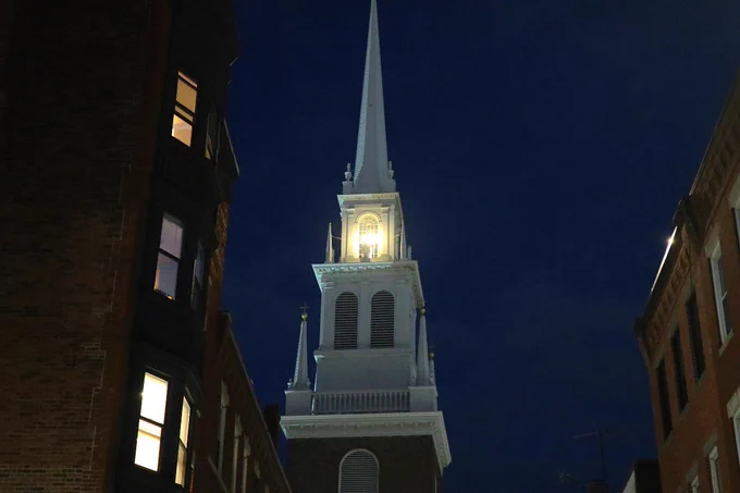 A photo of two lanterns shining from Old North Church's steeple in Boston. 