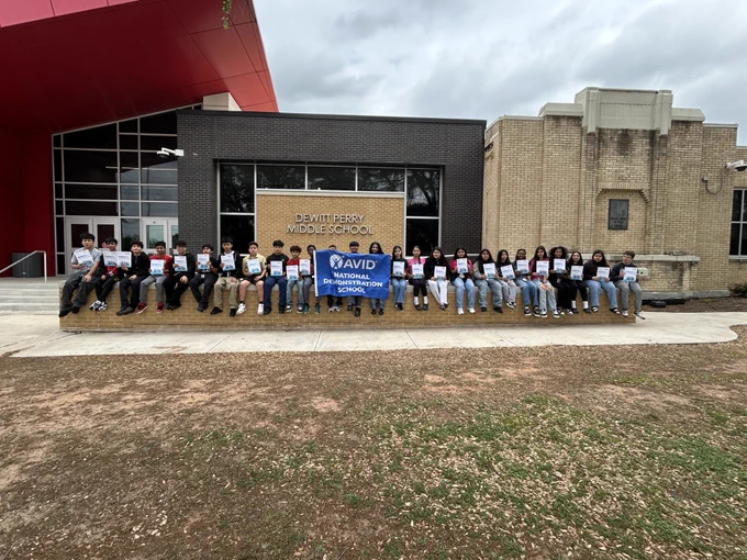 A group of people standing in front of Perry Middle School holding signs