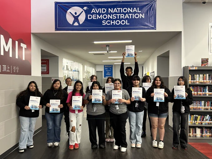 School hallway with students holding signs in front of Avid National Demonstration School banner.