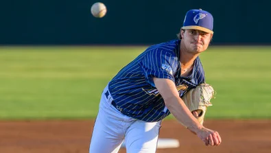 Tyler Bremner delivers a pitch wearing the a blue/pinstriped Tri-City Dust Devils jersey and white pants