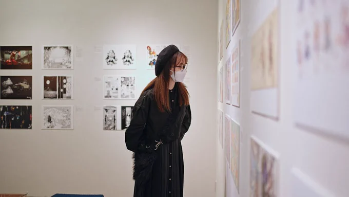 A woman in a mask examines art in a Shinjuku gallery, Tokyo, Japan.