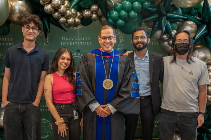 Dr. Obaid (center with his award and black and blue regalia) with his lab, who are standing in front of a green backdrop and balloon arch
