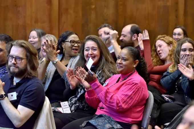 An audience clapping and smiling at an event.