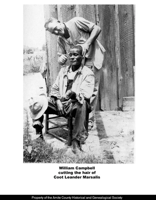 From the Amite County Historical and Genealogical Society Photographs Collection. A photograph of William Campbell cutting the hair of Coot Leander Marsalis.
