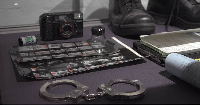 a pair of handcuffs is laid alongside the film negatives of photos taken during the riots