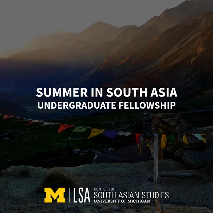 A scenic view of a mountainous landscape at sunset, with prayer flags hanging in the foreground. Text overlay reads "Summer in South Asia Undergraduate Fellowship." The University of Michigan LSA logo and "Center for South Asian Studies" are displayed at the bottom.
