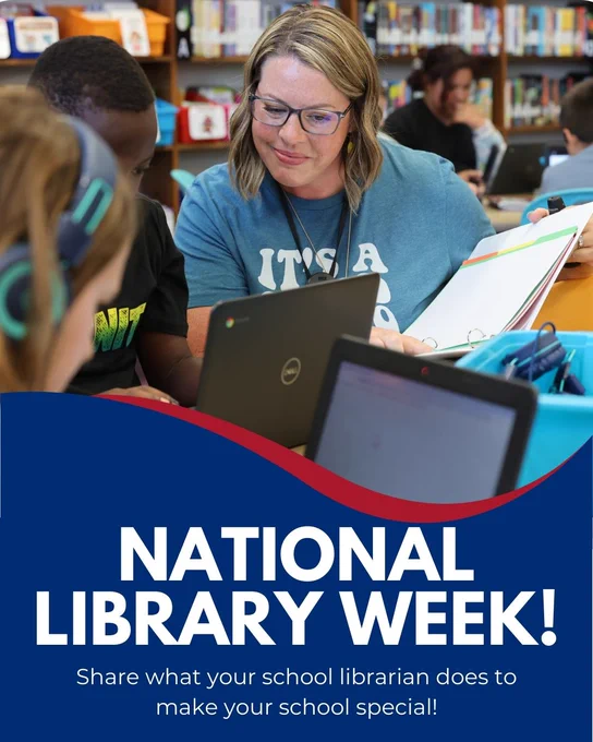 A woman with glasses and blonde hair sits at a table with several other people, using a laptop computer. A large blue and white banner reading "NATIONAL LIBRARY WEEK!" is displayed on the table.