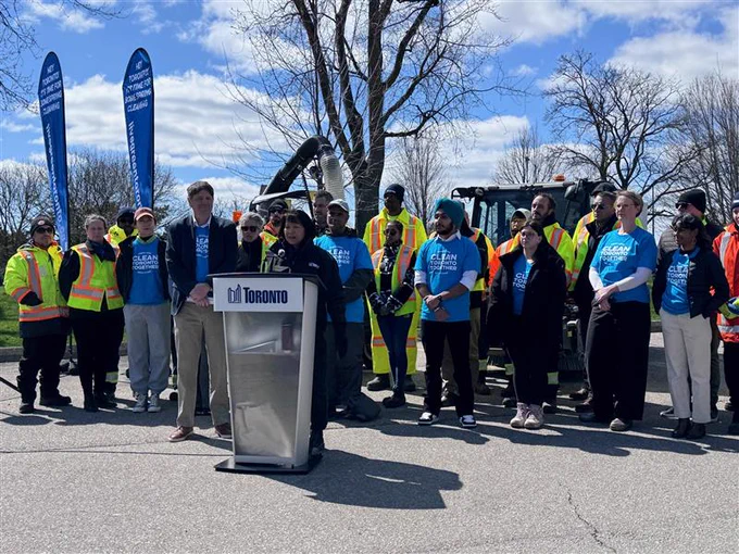 People at podium with Toronto sign on sunny day 