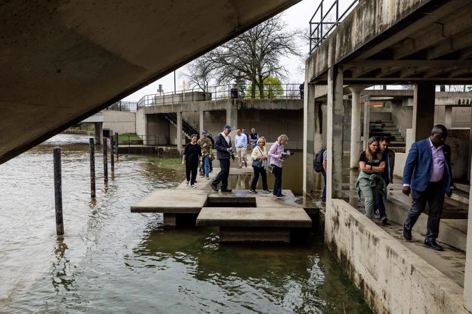 A group walks along the concrete Grand Fountain Block on the Flint River.