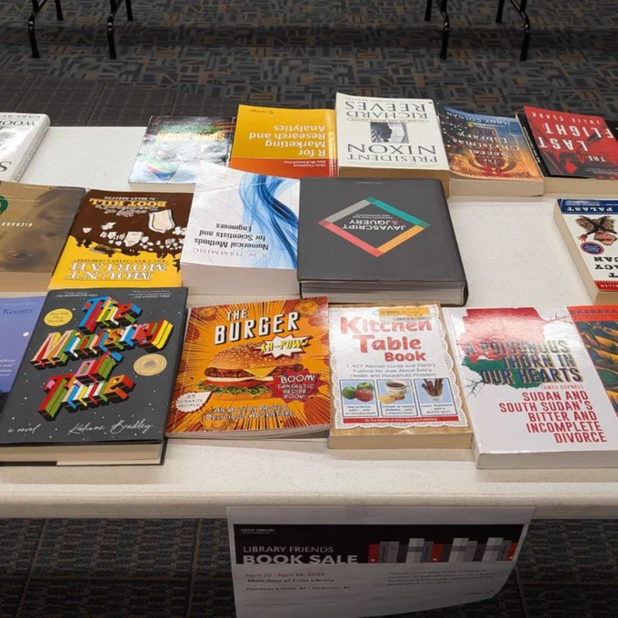 A mix of hardback and paperback books on a white table.