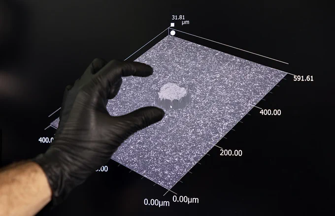 A gloved hand interacts with a 3D graph on a screen. 