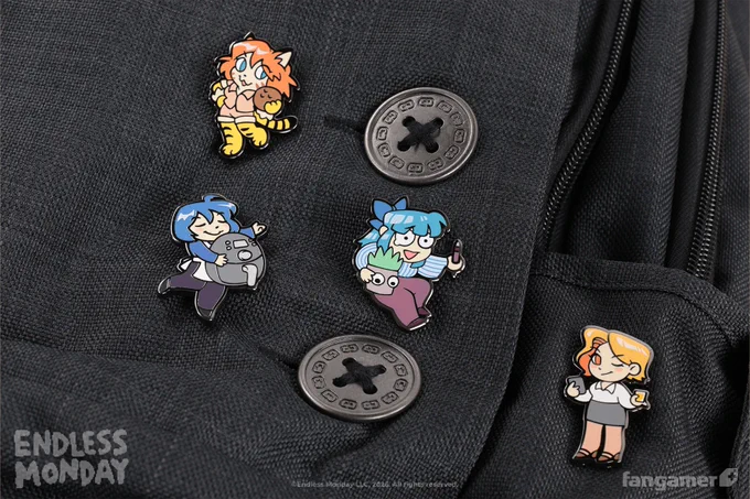 A closeup photo of the Endless Monday character pin set on a black bag, next to two large black buttons. It includes four colorful pins: Penny (and Li'l Succ), Miss Whiskey, Skye, and Tiger-chan. 