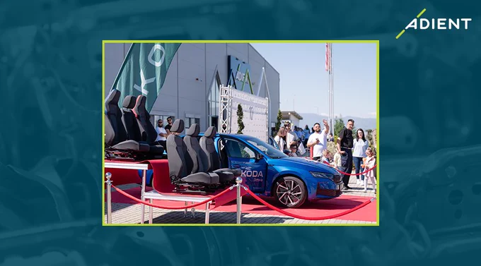 Blue Skoda car displayed outdoors with detached Adient seats arranged beside it.