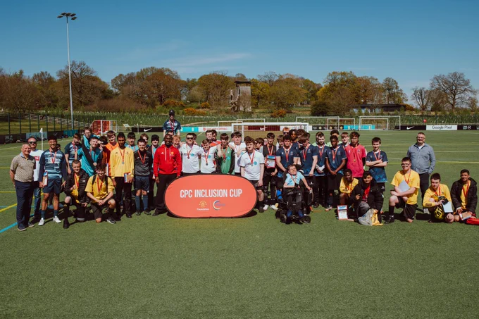 All players gather for a group photo with Andy Cole, standing behind a banner which says 'CPC Inclusion Cup'.