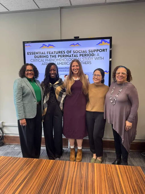 Five women stand in front of a screen with the text \"ESSENTIAL FEATURES OF SOCIAL SUPPORT DURING THE PERINATAL PERIOD: A CRITICAL PHENOMENOLOGICAL STUDY WITH AFRICAN AMERICA MOTHERS, Francesca Pratt, March 12th, 20@number.\"