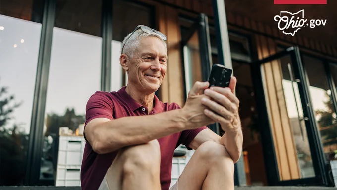 A man smiles as he accesses a website on his cellphone.