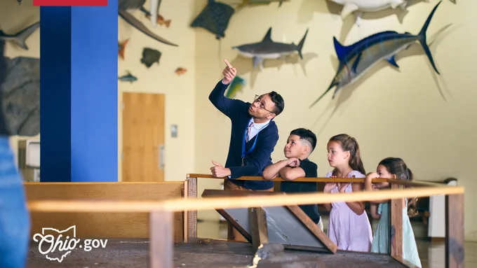 A natural museum tour guide points out specimens to a group of young children.