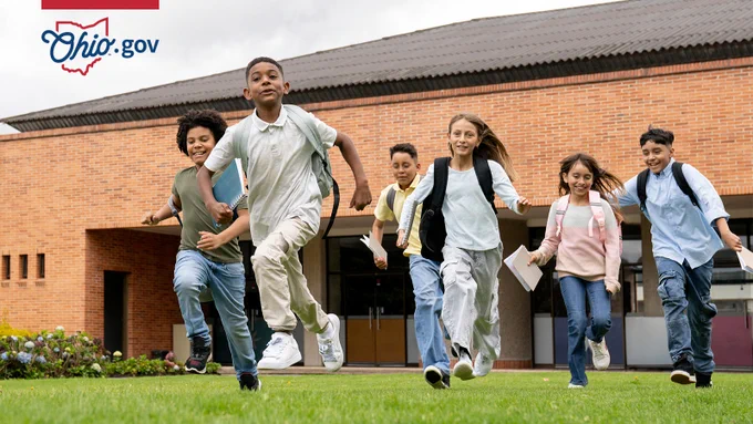 A diverse group of children run from the building at the end of a school day.