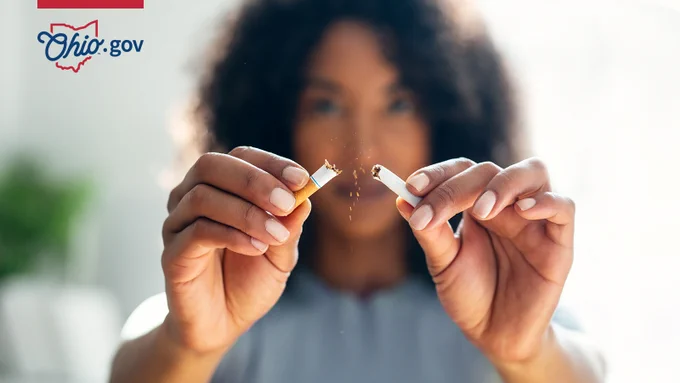 A woman breaks a cigarette in half.