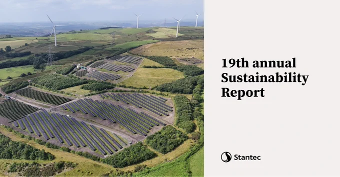 Aerial view of solar panels and wind turbines on green rolling hills representing renewable energy efforts.