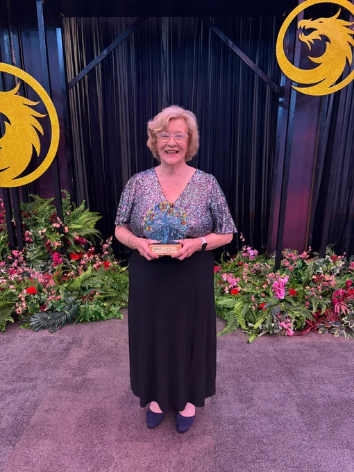 A picture of June Anderson, Chair of Clackmannanshire Tenants and Residents Federation, wearing a sparkly silver and black dress and holding her award.