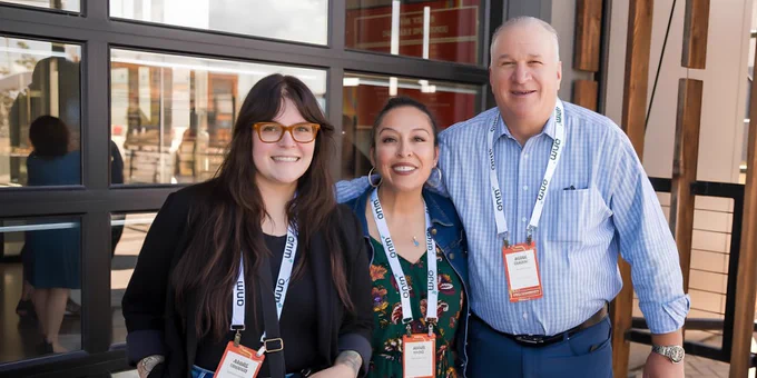 ActivateWork's Talent Solutions team, wearing conference name badges and smiling at the camera with arms around each other's shoulders