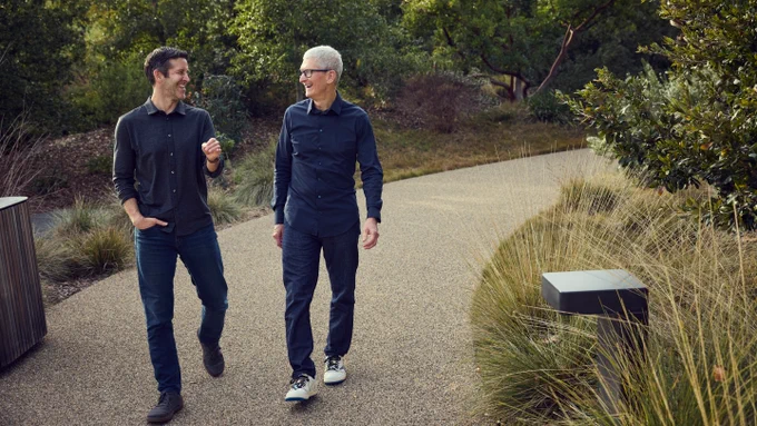 John and Tim walk side by side, talking at Apple Park.