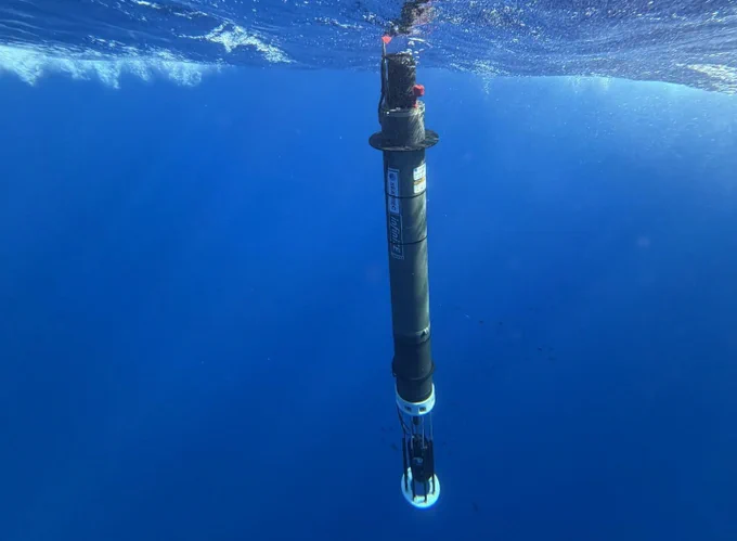 Image courtesy of Michael Zedelmair, Seatrec.

Alt text: A profiling float with Seatrec InfiniTE branding floats vertically in clear blue ocean water just below the surface.