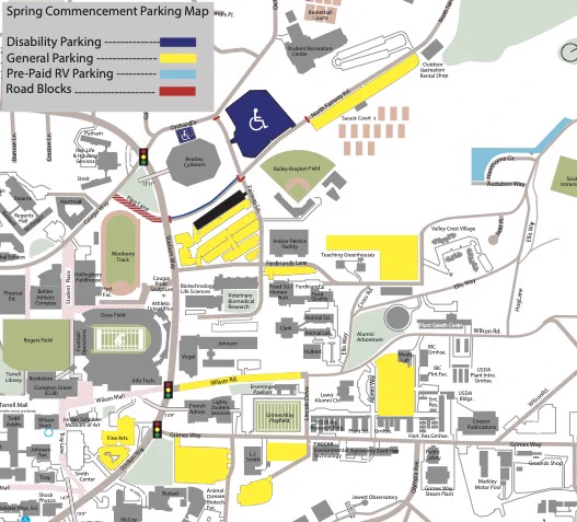 Map of the Washington State University Pullman campus showing parking locations and access routes for Spring Commencement. The map uses color coded zones to indicate different parking types, including general parking, disability parking, resident priority parking, and prepaid RV parking. Major campus buildings, athletic facilities, roads, garages, pedestrian areas, and landmarks are labeled. A parking key explains colors, permit requirements, and symbols, and directional arrows identify entrances, road closures, and routes from surrounding highways. A north arrow and distance scale are included.