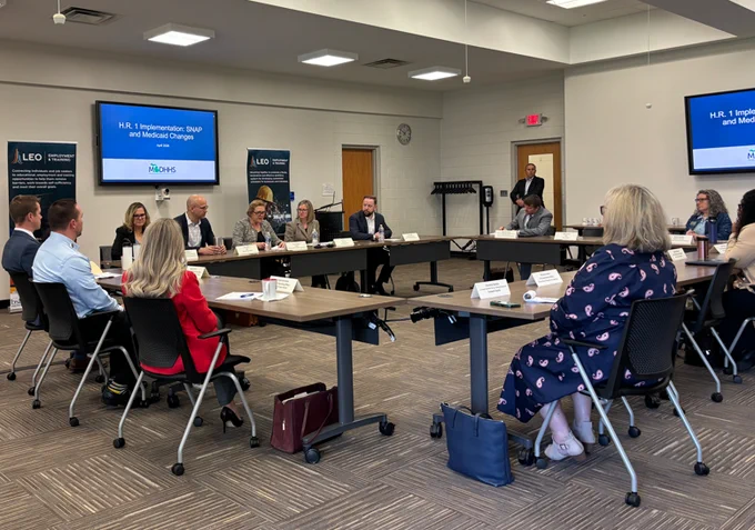 Group of local officials and legislators seated around a U-shaped conference table discussing H.R. 1 implementation on SNAP and Medicaid changes.
