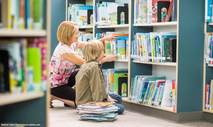 A woman and child browse books at a library.