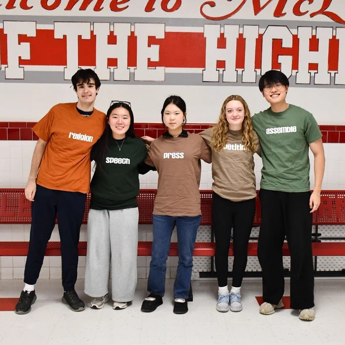 Five McLean High School students standing side by side in front of a school sign, each wearing a different colored shirt labeled with 'religion,' 'speech,' 'press,' 'petition,' and 'assemble.'