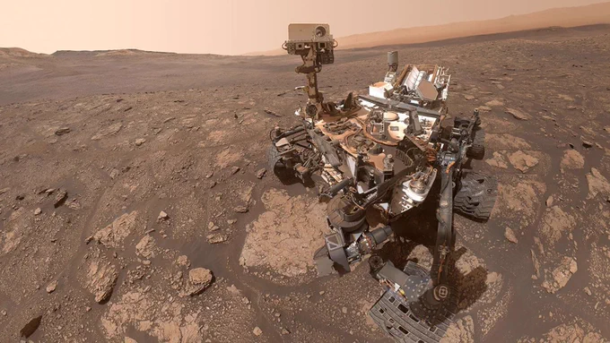 A \"selfie\" of NASA's Curiosity Mars rover, standing against a dark brown Martian landscape. Credit: NASA/JPL-Caltech/MSSS